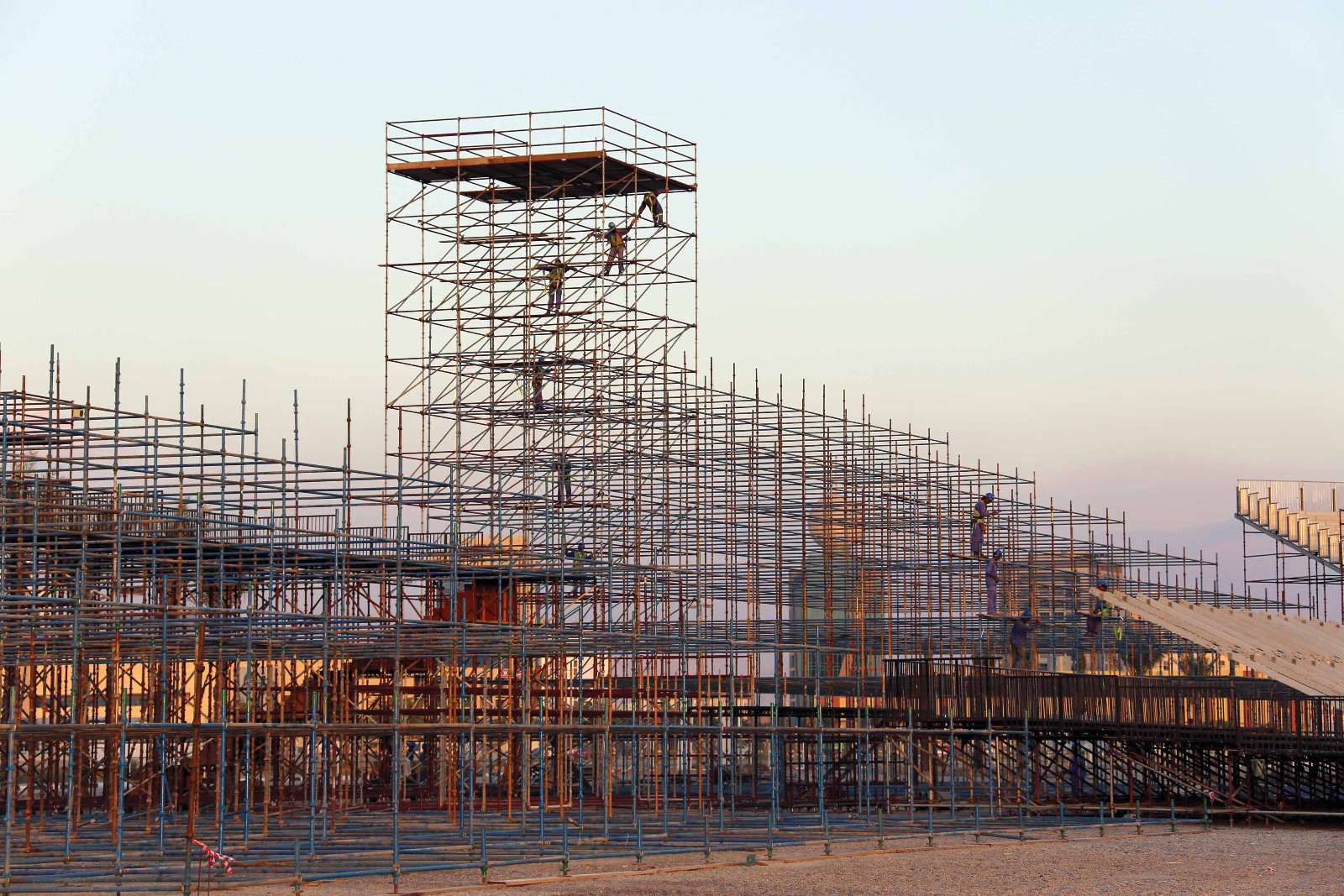 Apex Events crew building a large scaffolding structure at sunset